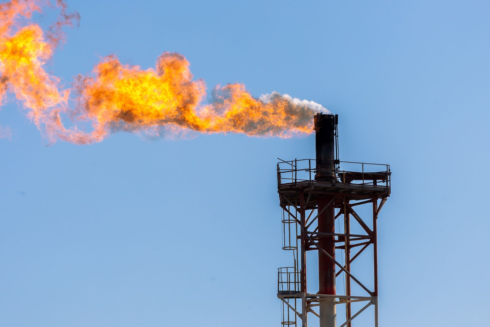 industrial flame tower emission against blue sky
